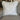 Decorative pillow with floral pattern and ruffled edges on a gray sofa.