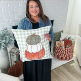 Stacey holding the September pillow cover with stacked pumpkins on it 