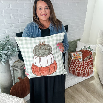 Stacey holding the September pillow cover with stacked pumpkins on it 