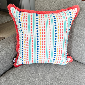 colorful striped summer pillow cover with orange edging on grey chair