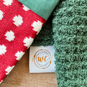 Close-up of red and white patterned fabric, green textured fabric, and a 'Wilshire Collections' label on a wooden surface.