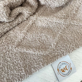 Close-up of a textured beige fabric with a visible label in the corner.