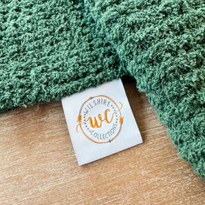 Green textured fabric with a 'Wilshire WC Collections' label on a wooden surface