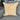 Yellow throw pillow with white floral embroidery and patterned fabric panel, displayed on a gray couch.
