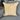 Yellow throw pillow with white floral embroidery and patterned fabric panel, displayed on a gray couch.
